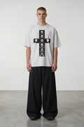 Camiseta blanca de algodón de Estudio Mora con estampado gráfico de cruz en blanco y negro y cuello redondo.