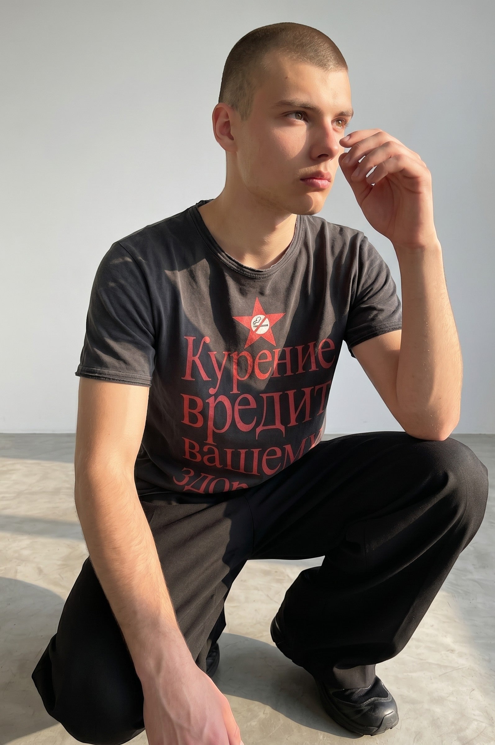 Camiseta gris oscuro de algodón de Estudio Mora con estampado rojo de estrella y texto cirílico. Corte relajado.