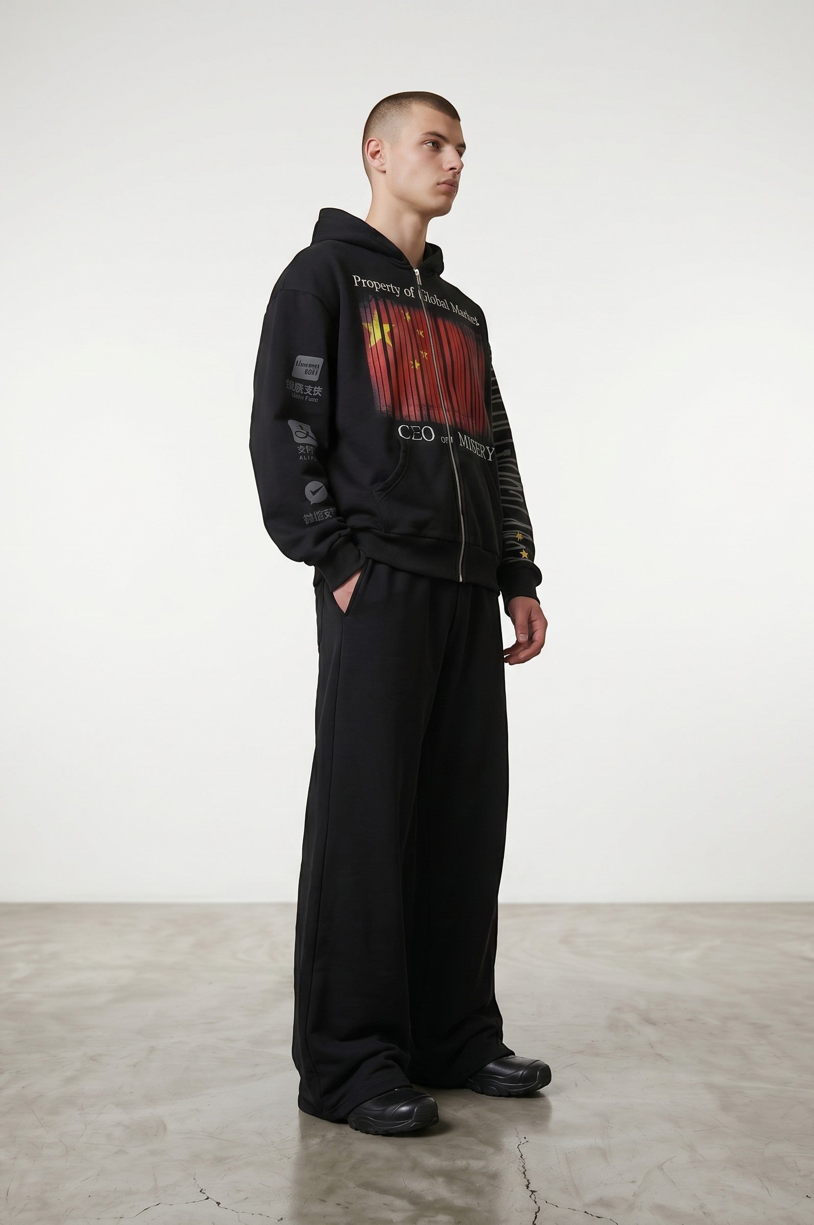 Estudio Mora Eternal Zip-Up sudadera negra con cremallera frontal, capucha y estampado gráfico de la bandera china y texto.