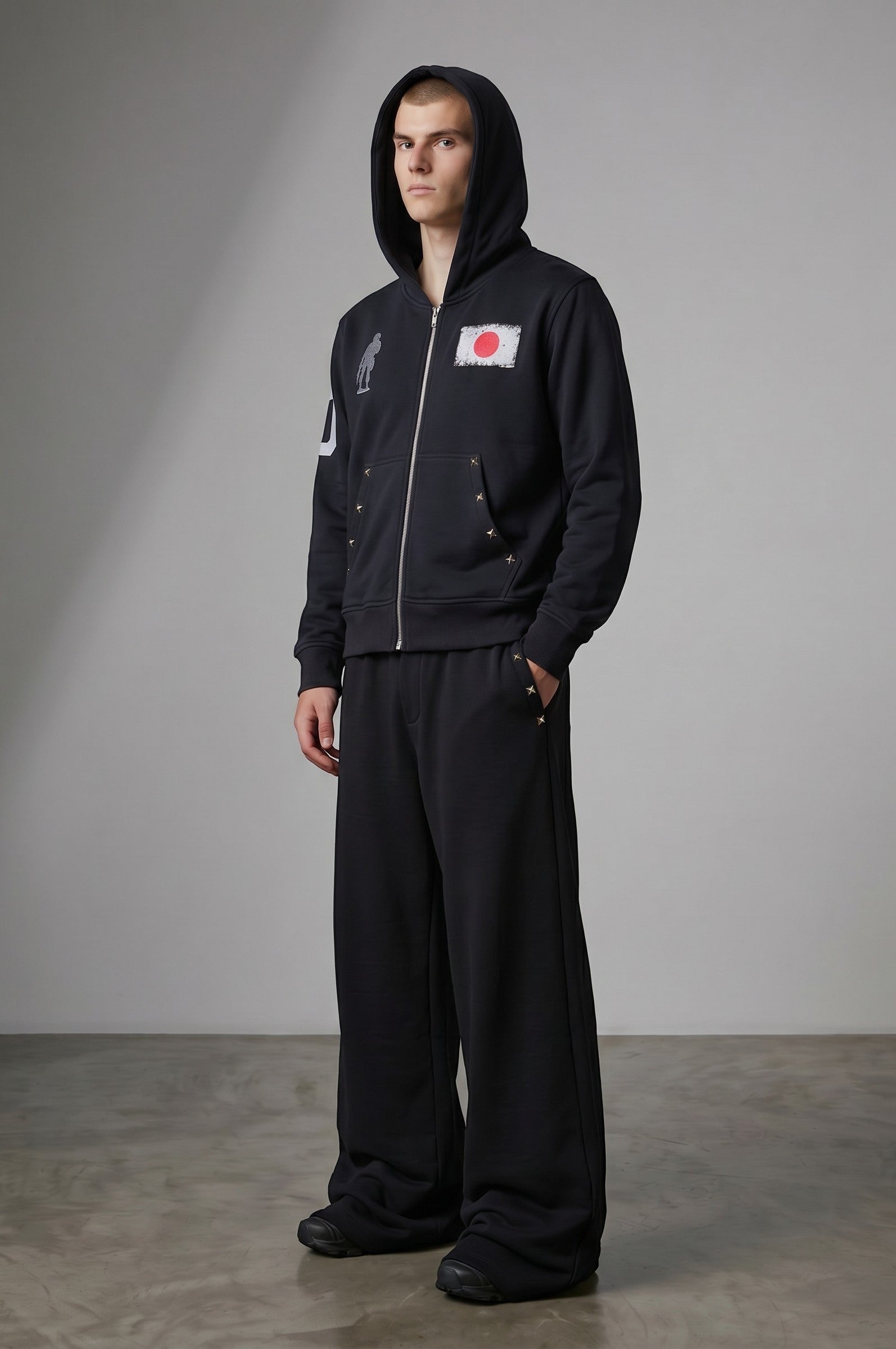 Estudio Mora sudadera con cremallera negra, con estampado de la bandera de Japón en el pecho y detalles de tachuelas.