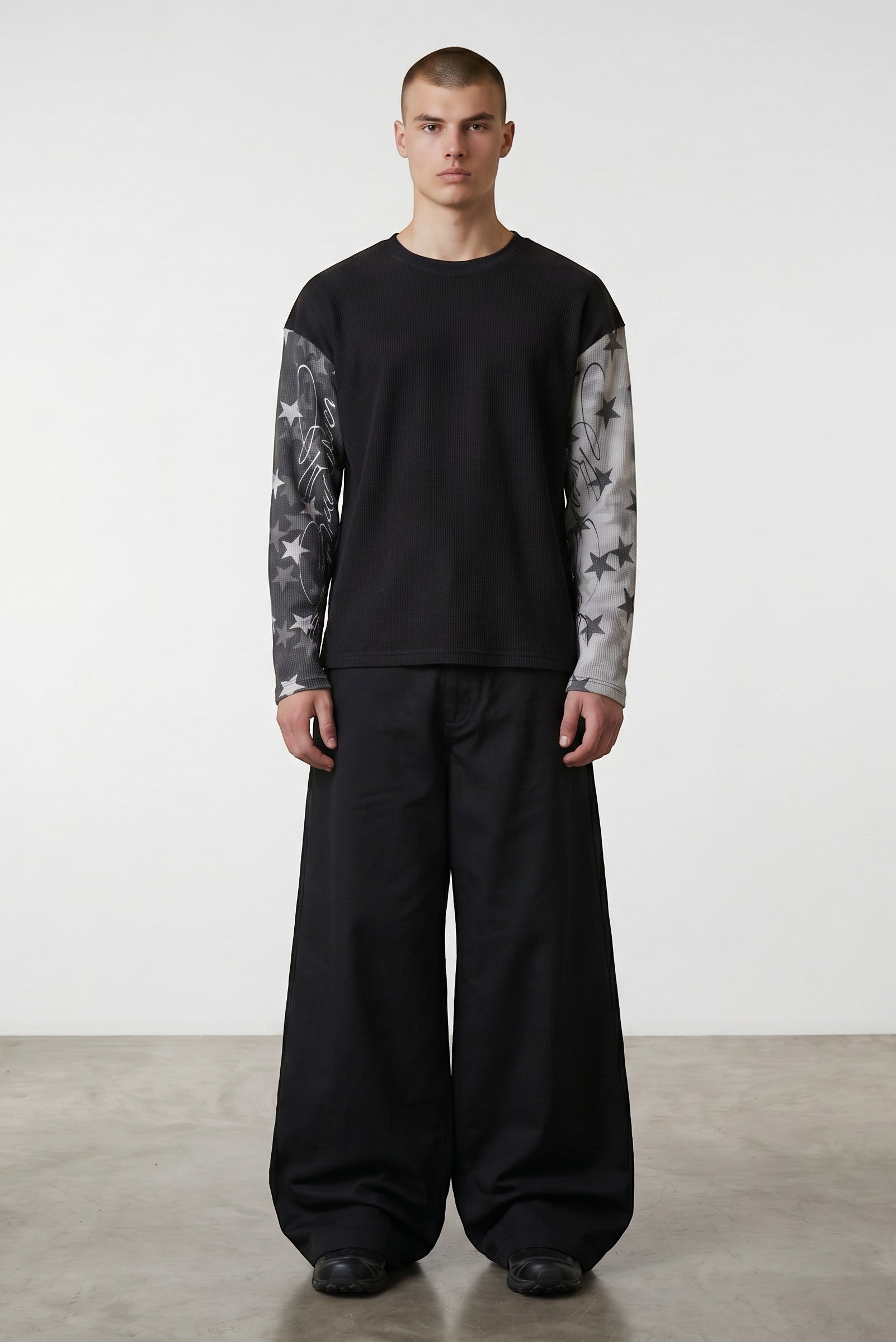 Estudio Mora sudadera negra de manga larga con estampado de estrellas y texto en las mangas, cuerpo de gofre.