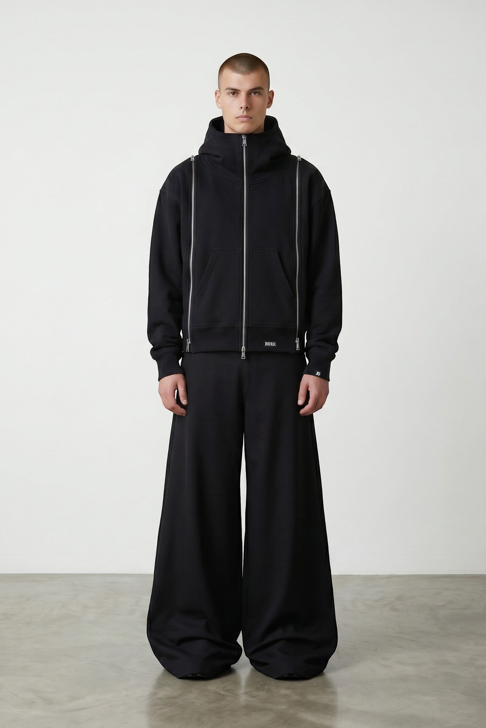 Estudio Mora sudadera negra con cremallera completa y cuello alto, con detalles de cremallera en los laterales.