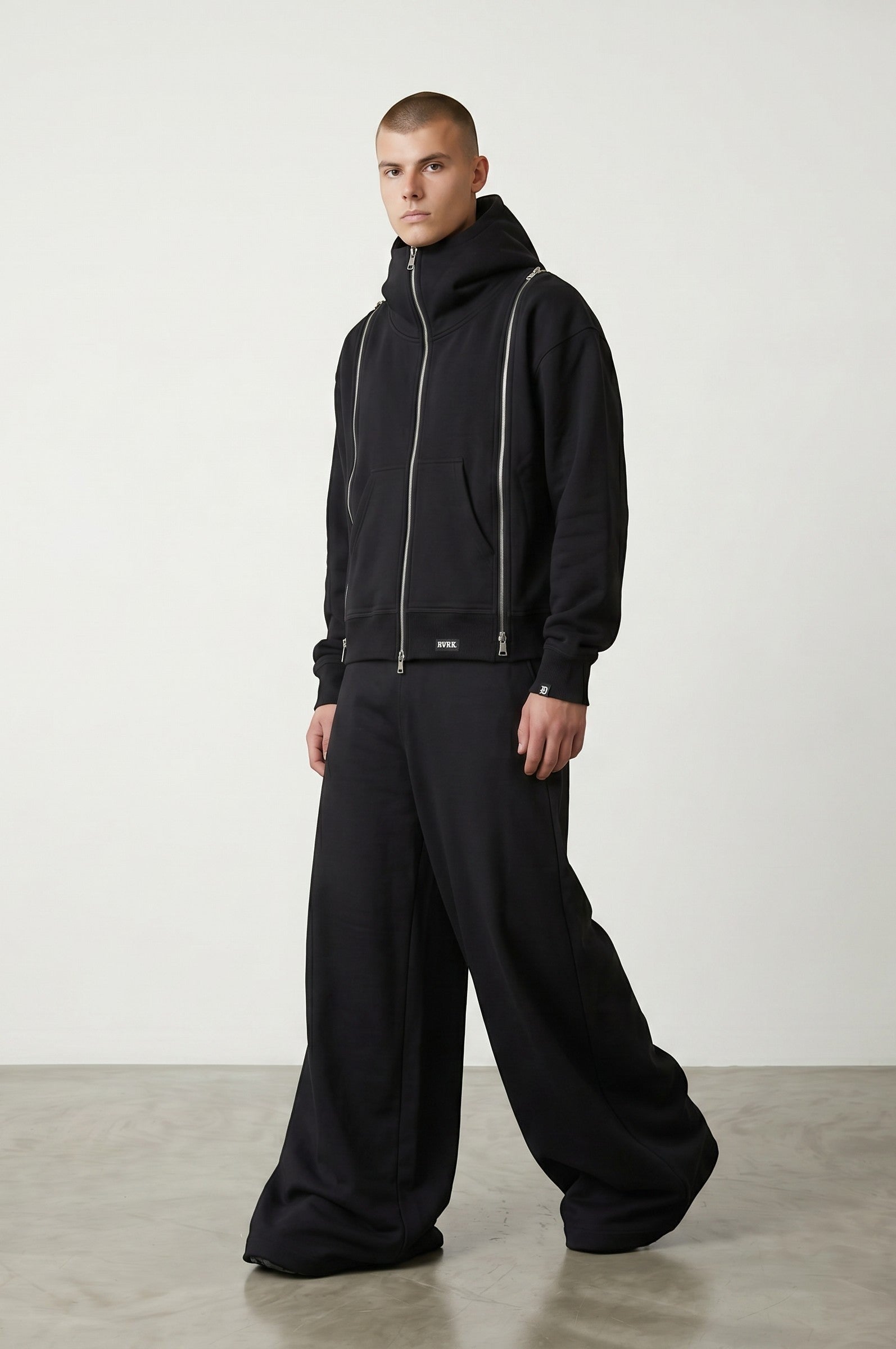 Estudio Mora sudadera negra con cremallera y cuello alto, pantalones anchos negros.