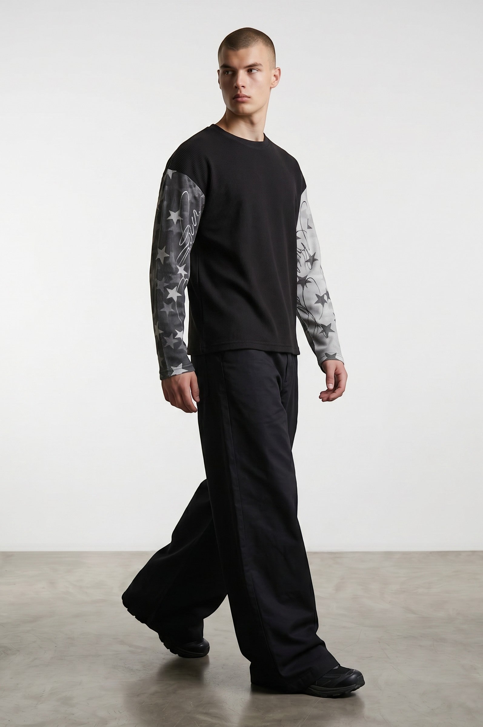 Estudio Mora sudadera negra de manga larga con estampado de estrellas en las mangas y tejido texturizado.