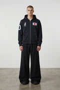 Estudio Mora sudadera con cremallera negra con estampado de la bandera de Japón y figura de soldado, mangas con detalle de número.